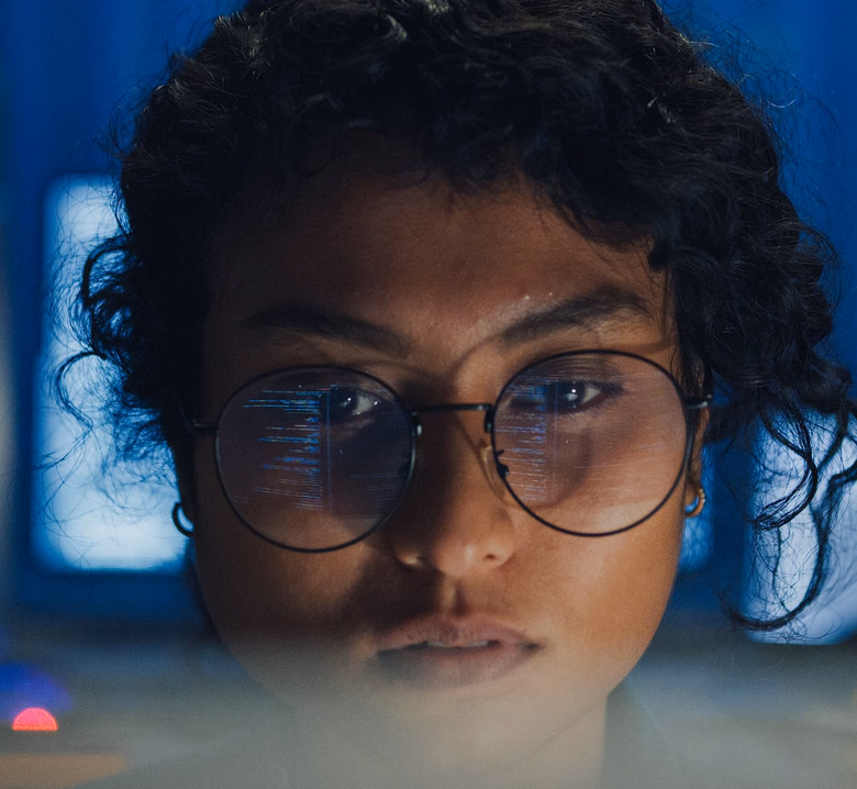 An analyst studying code reflected in her glasses